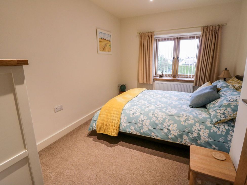 A bedroom with a bed and window at Grange Cottage in Crediton