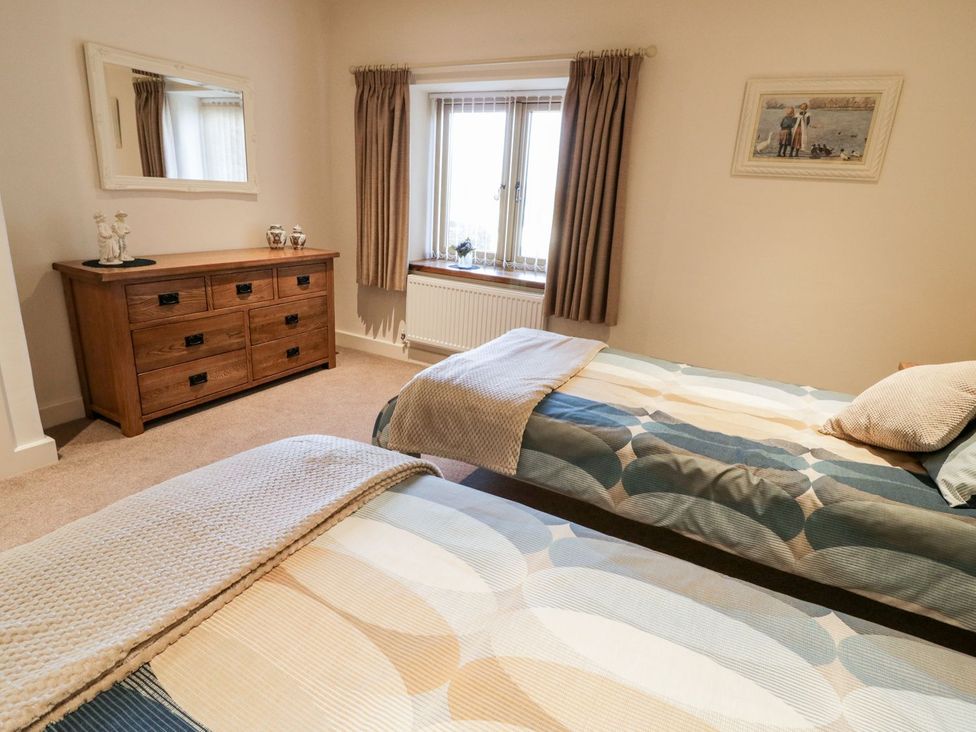 A bedroom with two beds and a dresser at Grange Cottage in Crediton