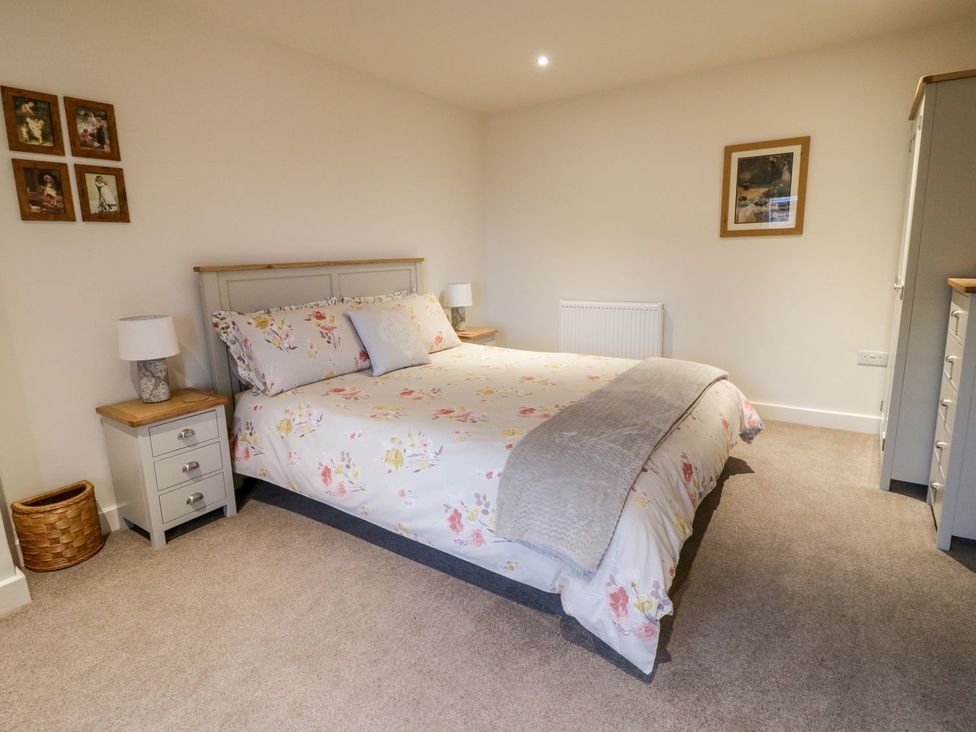 A bedroom with a bed and two bedside tables at Grange Cottage in Crediton