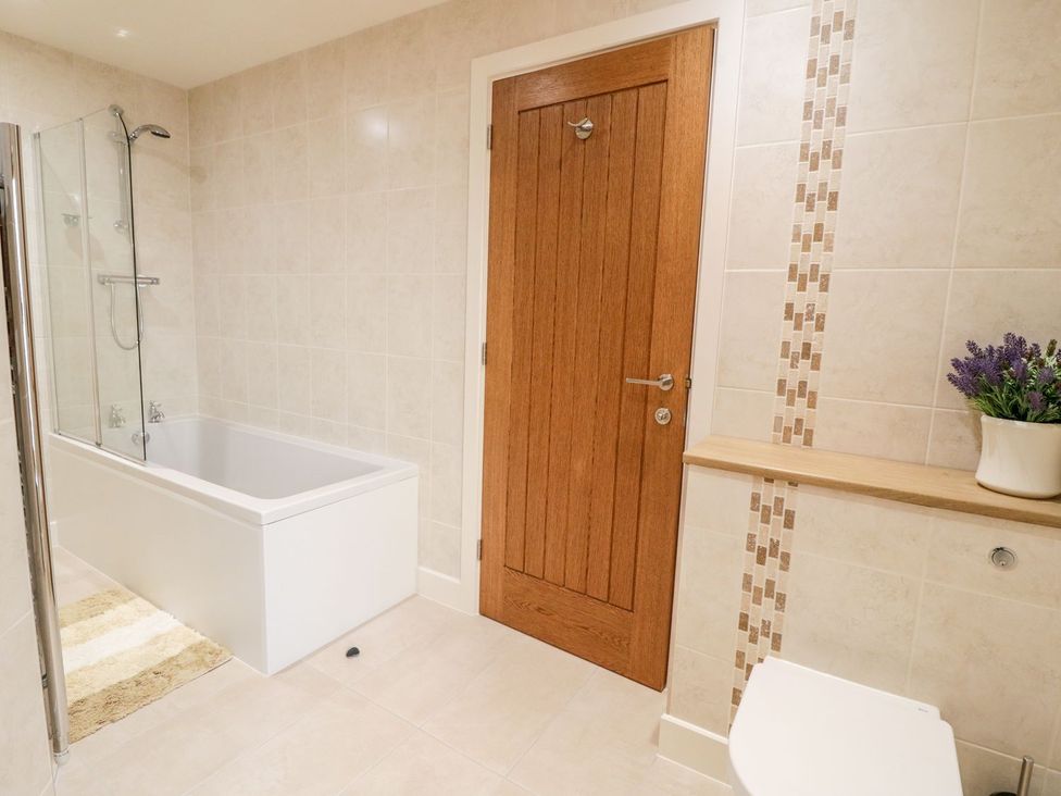 A bathroom with a bathtub and shower at Grange Cottage in Crediton
