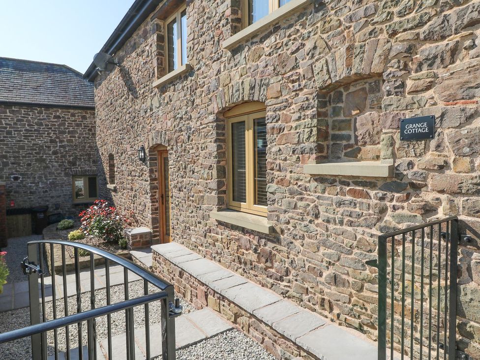An outdoor view of Grange Cottage with stone wall and pathway in Crediton