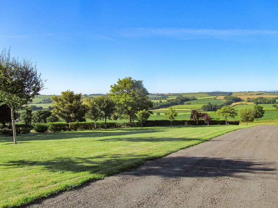 An outdoor view with a grassy area and trees at Grange Cottage in Crediton