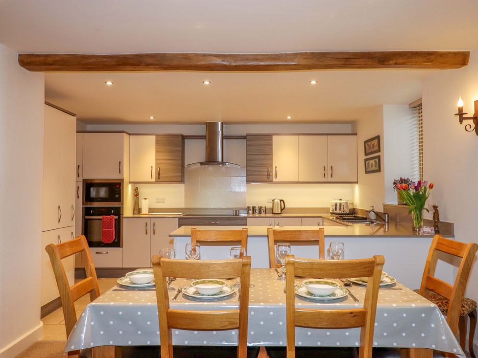 A kitchen with a dining table and cooking appliances at Grange Cottage in Coldridge
