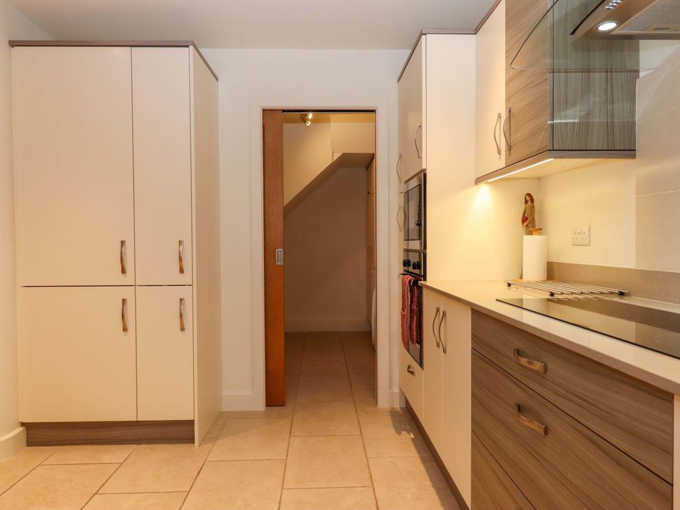 A kitchen with cabinets, an oven, and a doorway at Grange Cottage in Coldridge