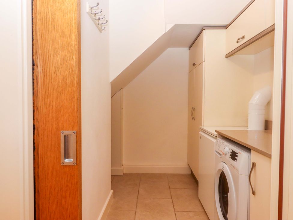 A laundry room with a washing machine and cabinets at Grange Cottage in Coldridge