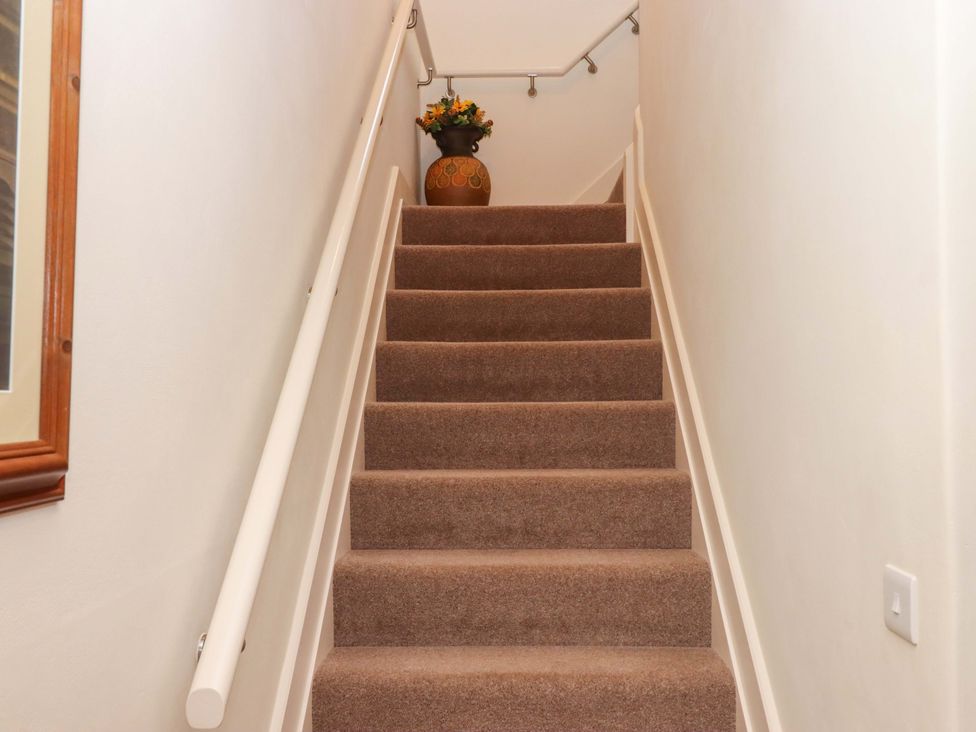 A staircase with a vase and flowers at Grange Cottage Coldridge