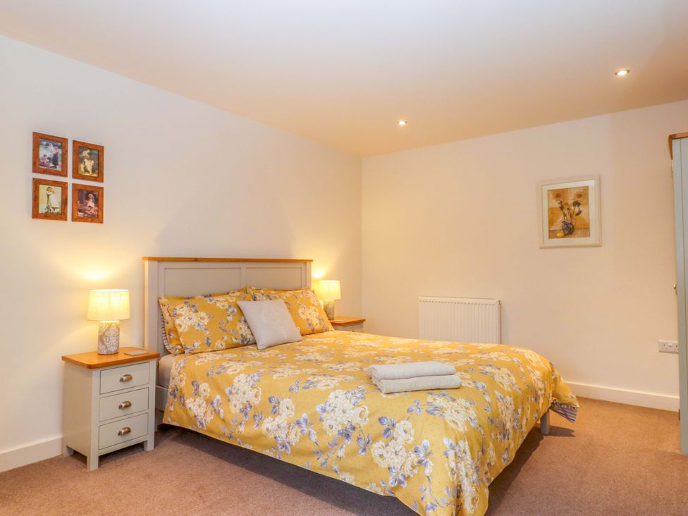 A bedroom with a bed and framed pictures at Grange Cottage in Coldridge