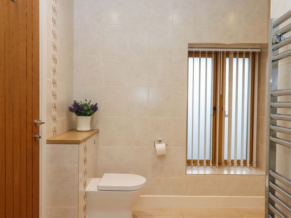 A bathroom with a toilet, window, and shelf at Grange Cottage in Coldridge