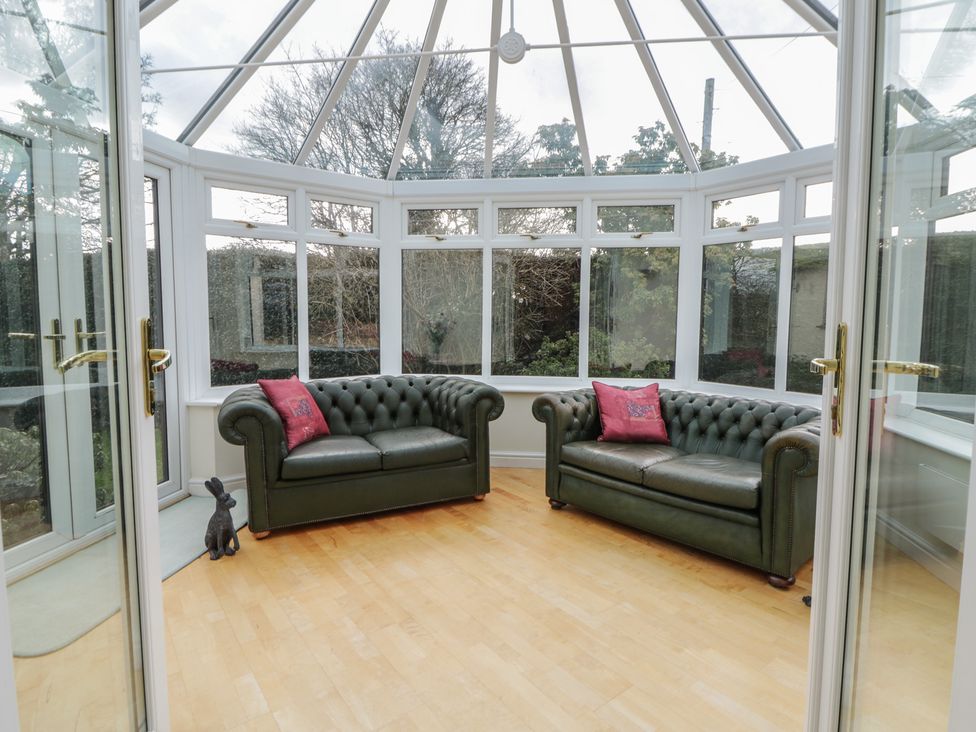 A conservatory with two sofas and a table at Summerhill in Hereford