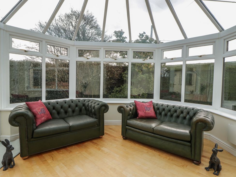 A conservatory with two sofas and rabbit figurines at Summerhill in Hereford