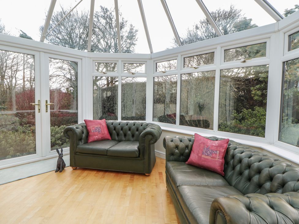 A conservatory with sofas and large windows at Summerhill in Hereford