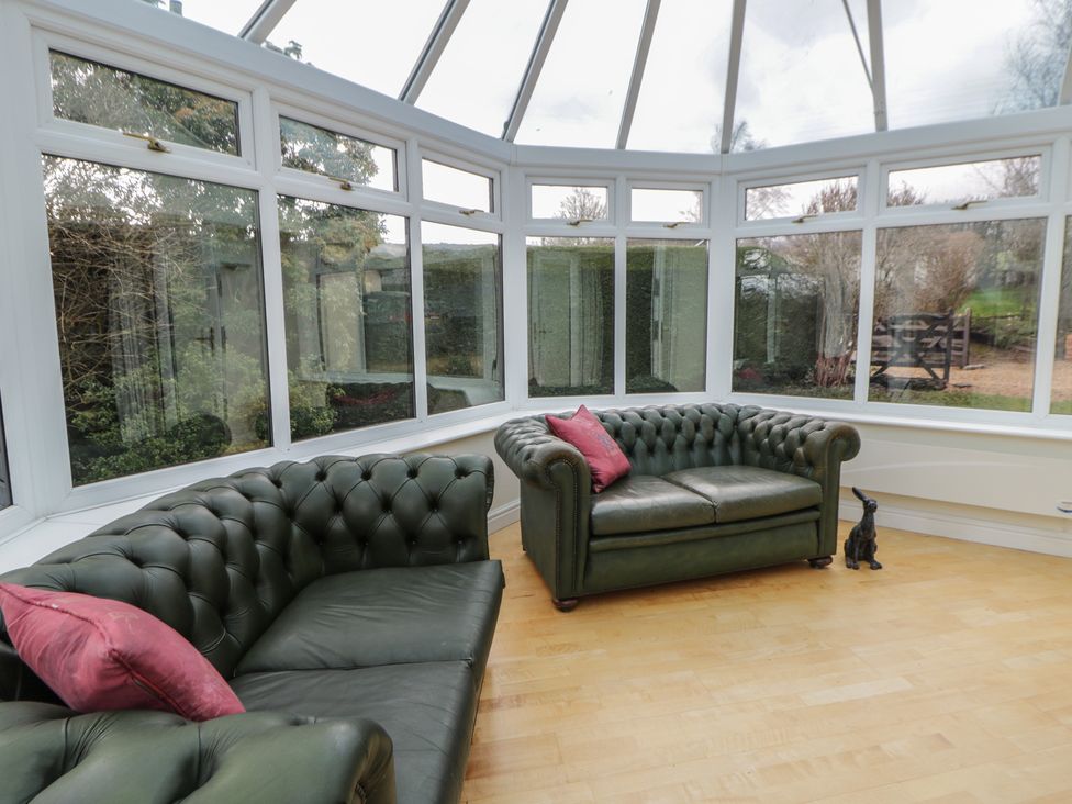 A conservatory with sofas and large windows at Summerhill in Hereford