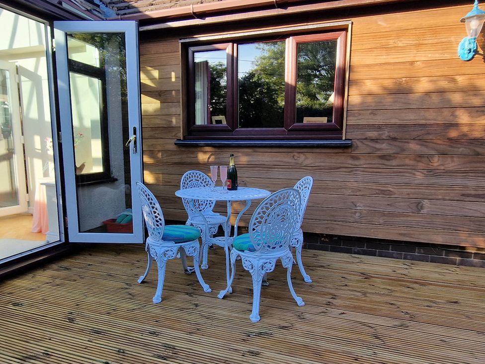 A table and chairs with a bottle and glasses in an outdoor area at Summerhill Near Glasbury