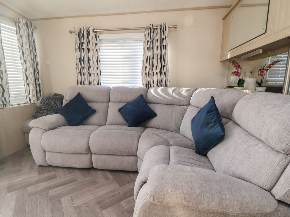 A living room featuring a sofa with cushions and curtains at CG 55