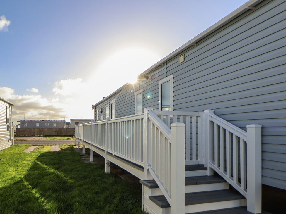 A house with a deck and railing under a sunny sky at CG 55