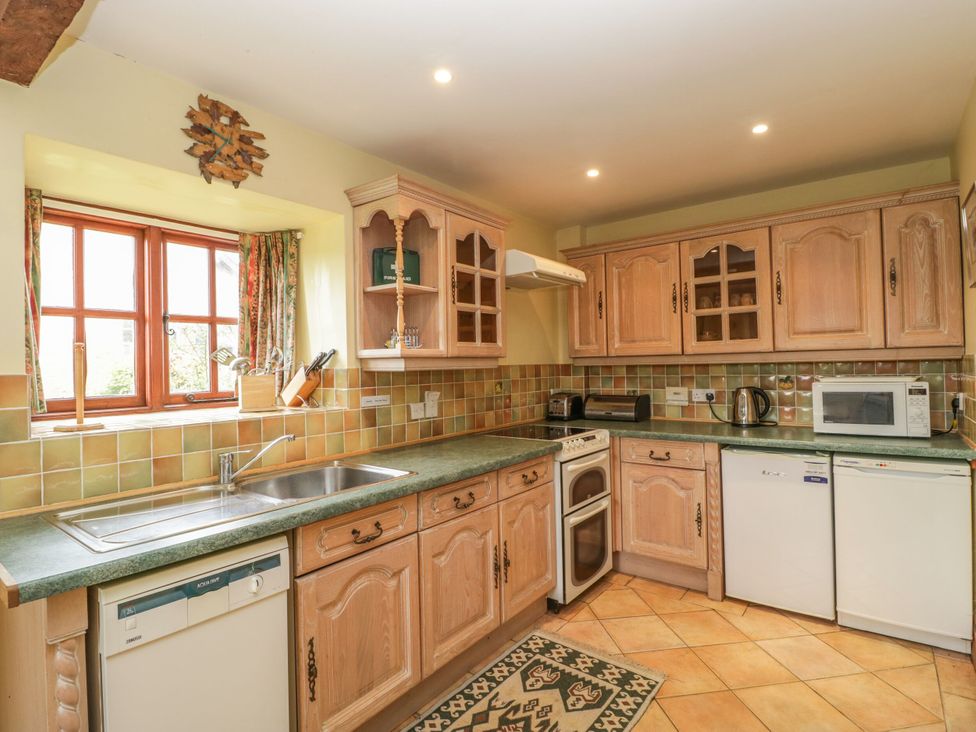 A kitchen with wooden cabinets and appliances at The Stables in Sturminster Newton