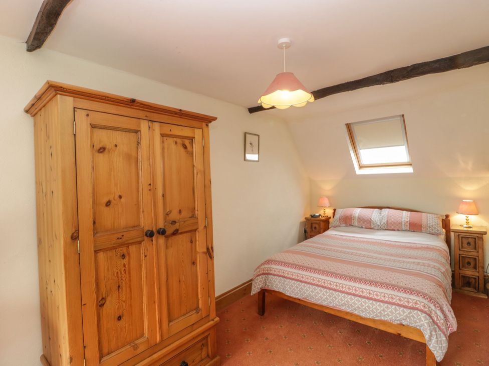 A bedroom with a bed and wardrobe at The Stables in Sturminster Newton
