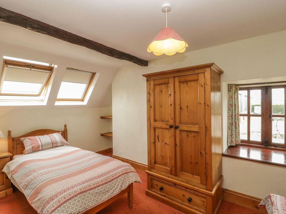 A bedroom with a bed and wooden wardrobe at The Stables in Sturminster Newton