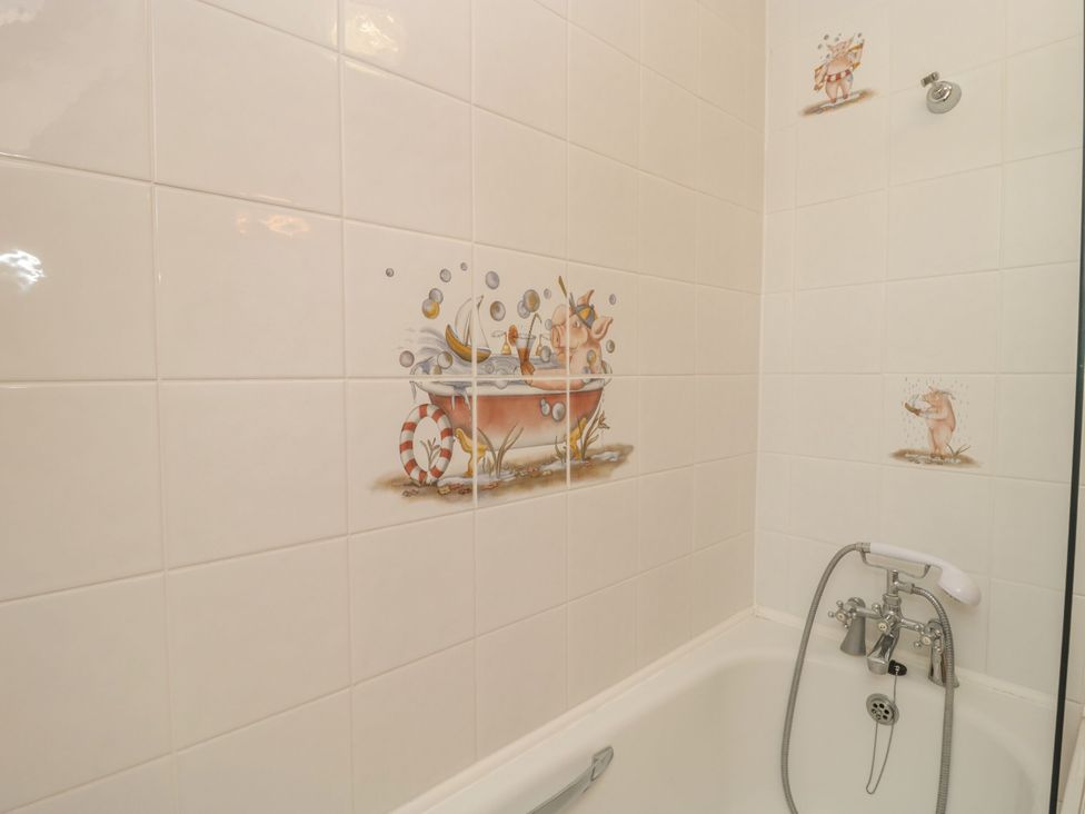 A bathroom with a bathtub and decorative tiles at The Stables in Sturminster Newton