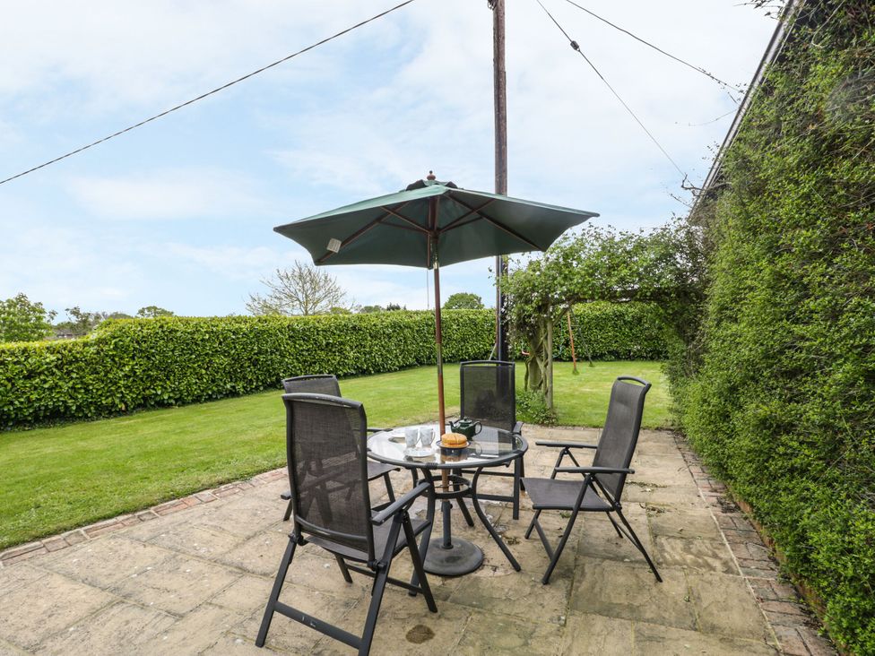 A garden with a table and chairs under an umbrella at The Stables in Sturminster Newton