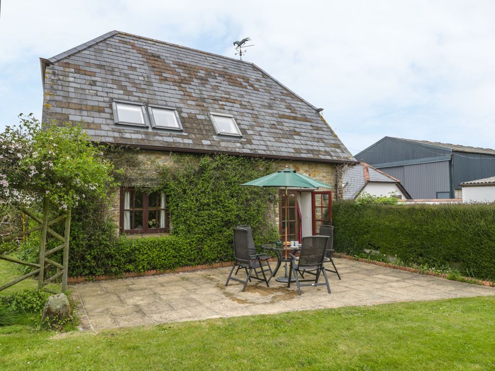 An outdoor patio with a table and chairs at The Stables in Sturminster Newton