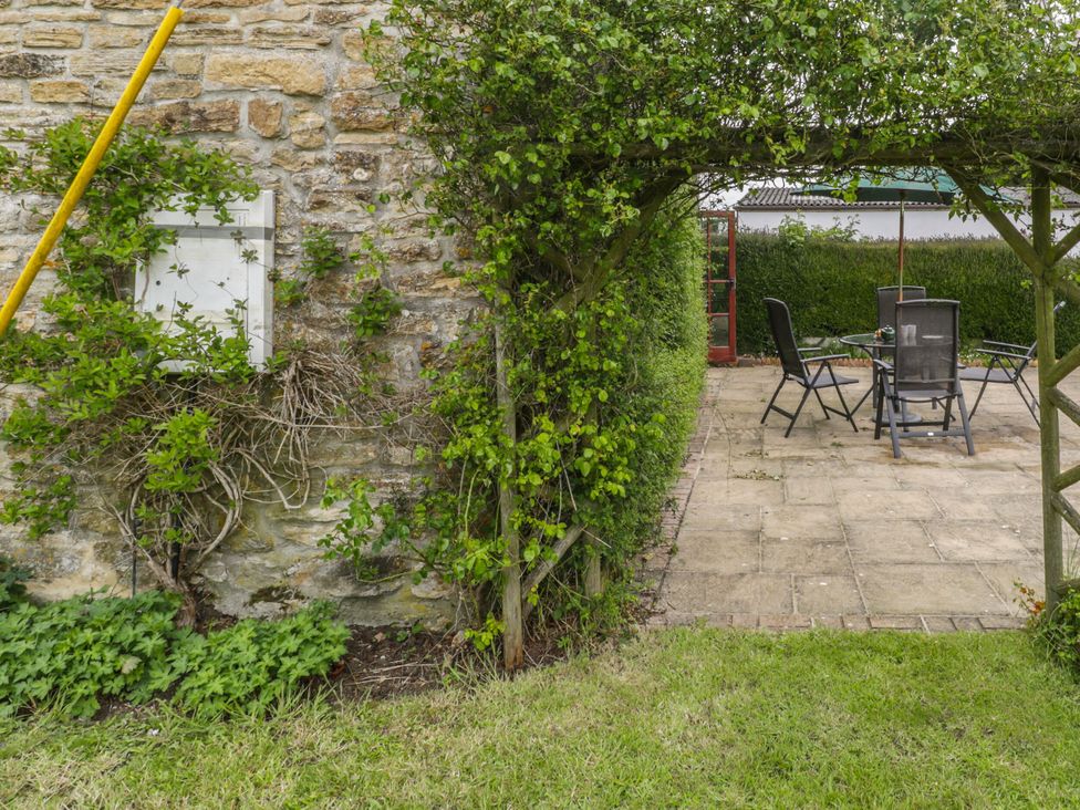 A garden area with a stone wall and patio furniture at The Stables in Sturminster Newton