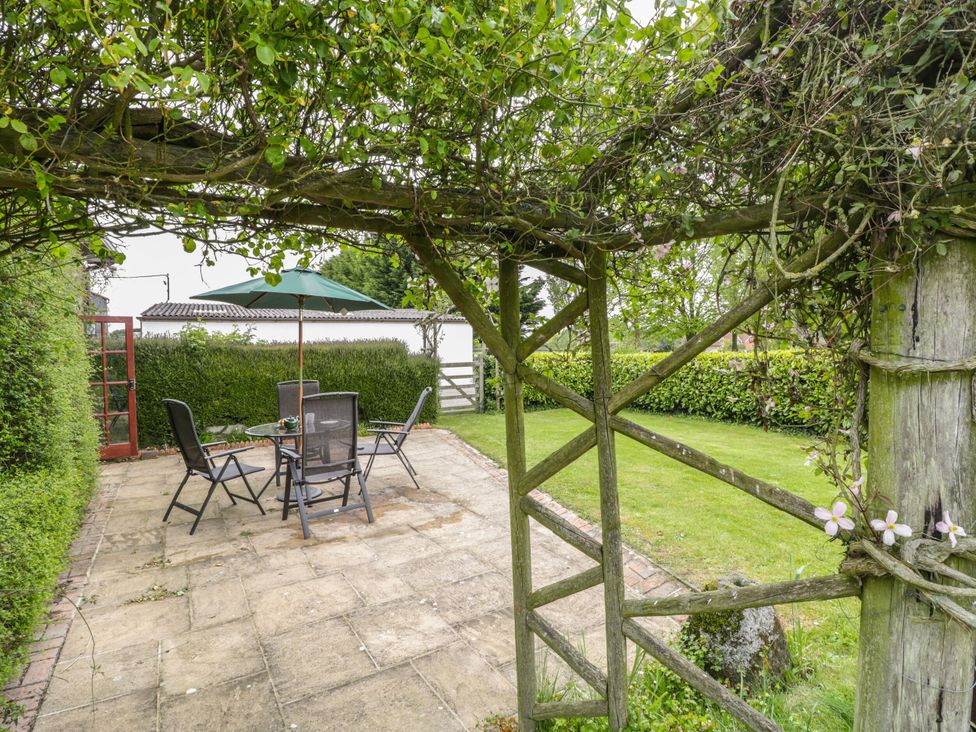 A garden with a patio set and umbrella at The Stables in Sturminster Newton