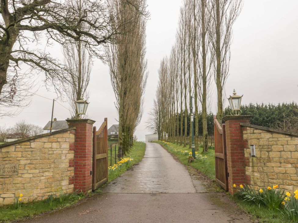 A driveway with a gate and trees on either side at The Stables in Sturminster Newton