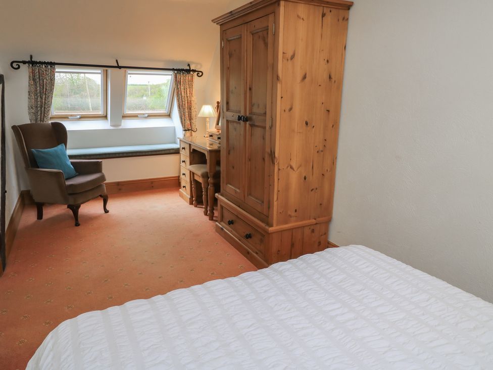 A bedroom with a bed, wardrobe, chair and desk at The Stables in Fifehead Neville near Hazelbury Bryan