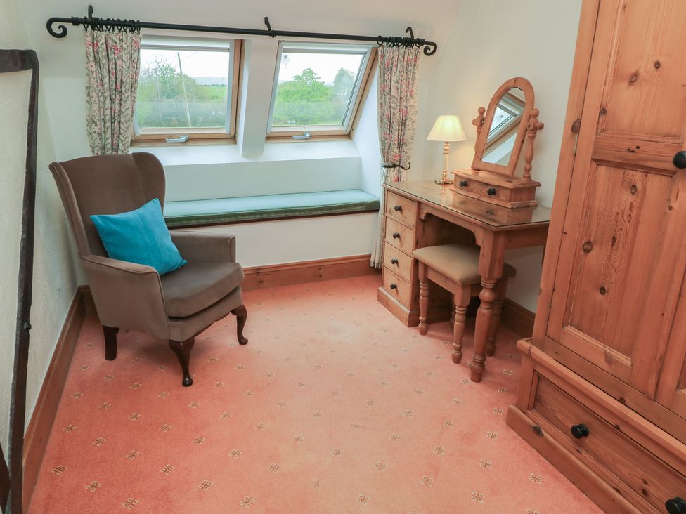 A bedroom with a chair, vanity table, and wardrobe at The Stables in Fifehead Neville near Hazelbury Bryan