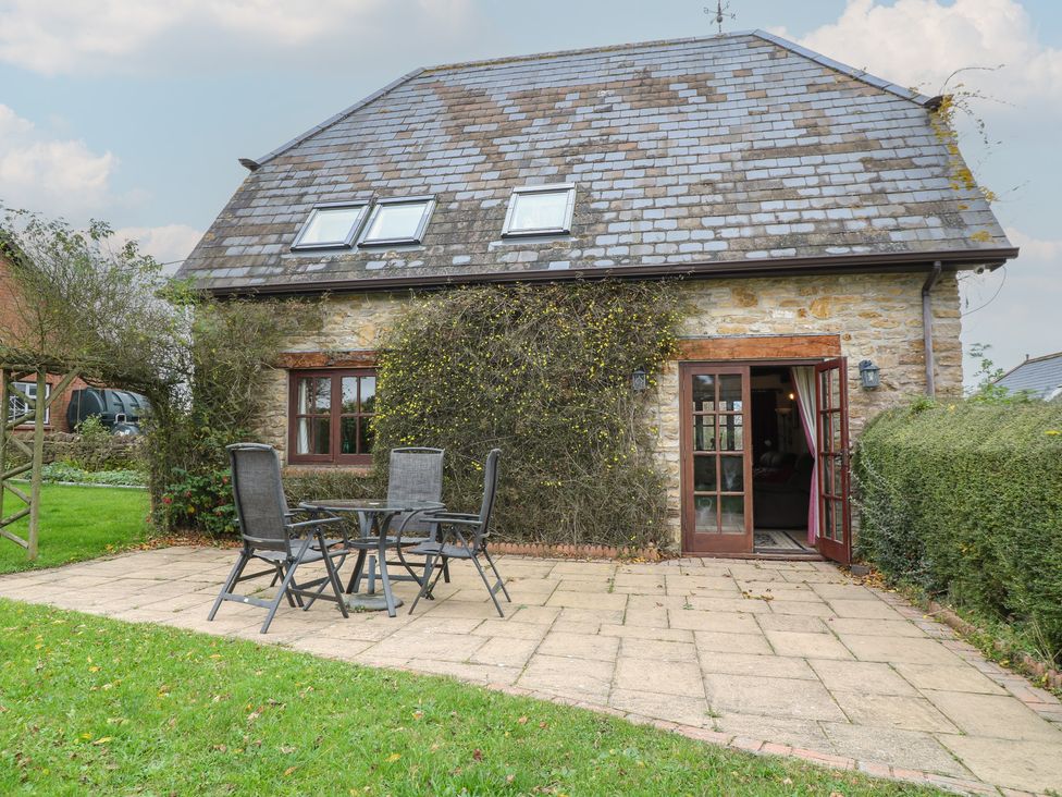 A house with a patio and table and chairs at The Stables Fifehead Neville near Hazelbury Bryan