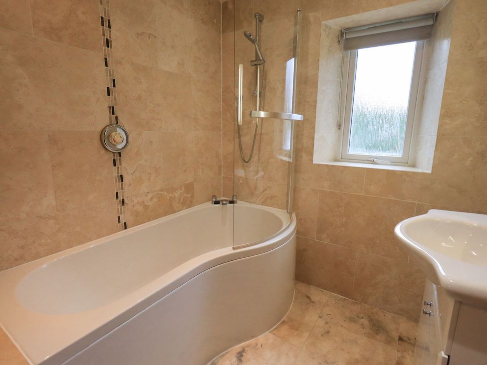 A bathroom with a bathtub, shower, and sink at Thrang View, Chapel Stile