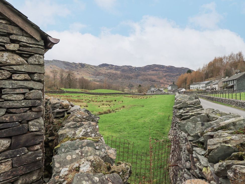 A field with a stone wall and buildings nearby at Thrang View in Chapel Stile