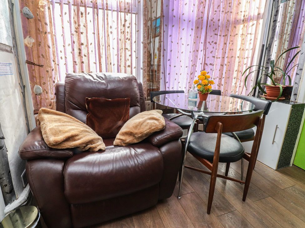 A conservatory with a brown armchair and a glass table at Number 3 in Blackpool