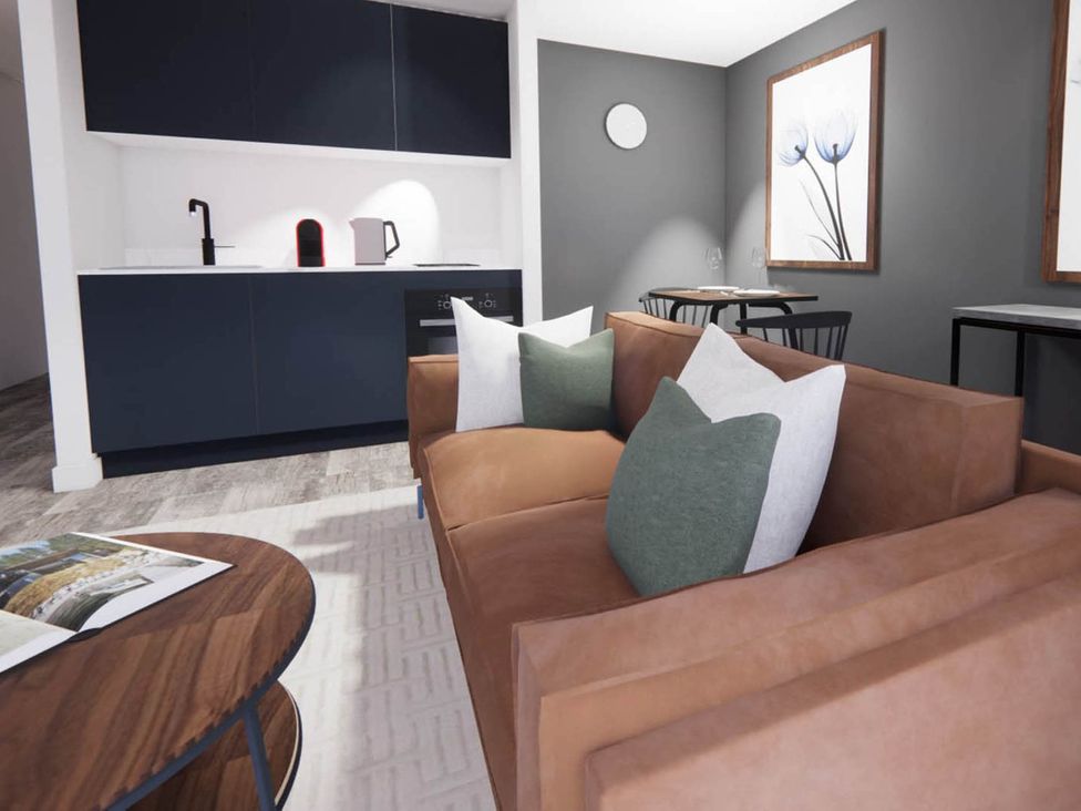 A living room with a sofa and kitchen area at Arvo Suite 1.0 in Marhamchurch