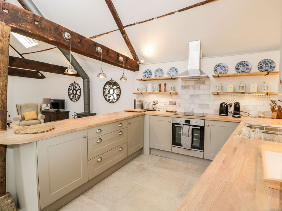 A kitchen with a kitchen island and shelves at The Old Swill House in Foxham