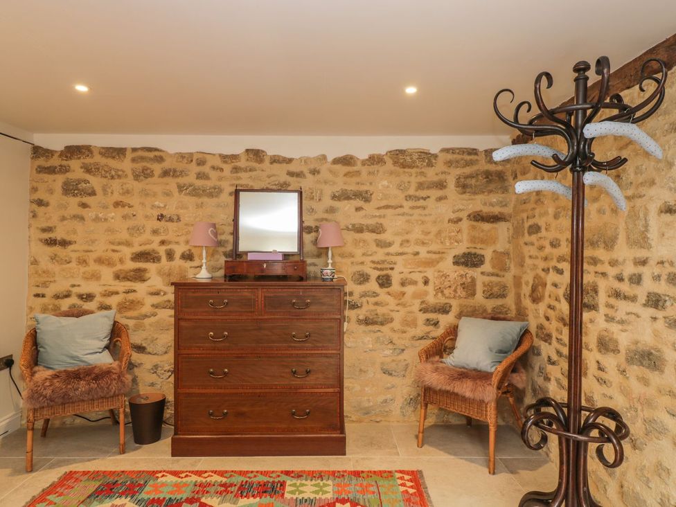 A room with a dresser, chair, and coat rack at The Old Swill House in Foxham