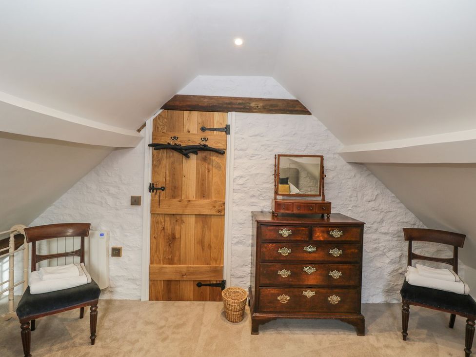 A bedroom with a wooden door and antique furniture at The Old Swill House in Foxham