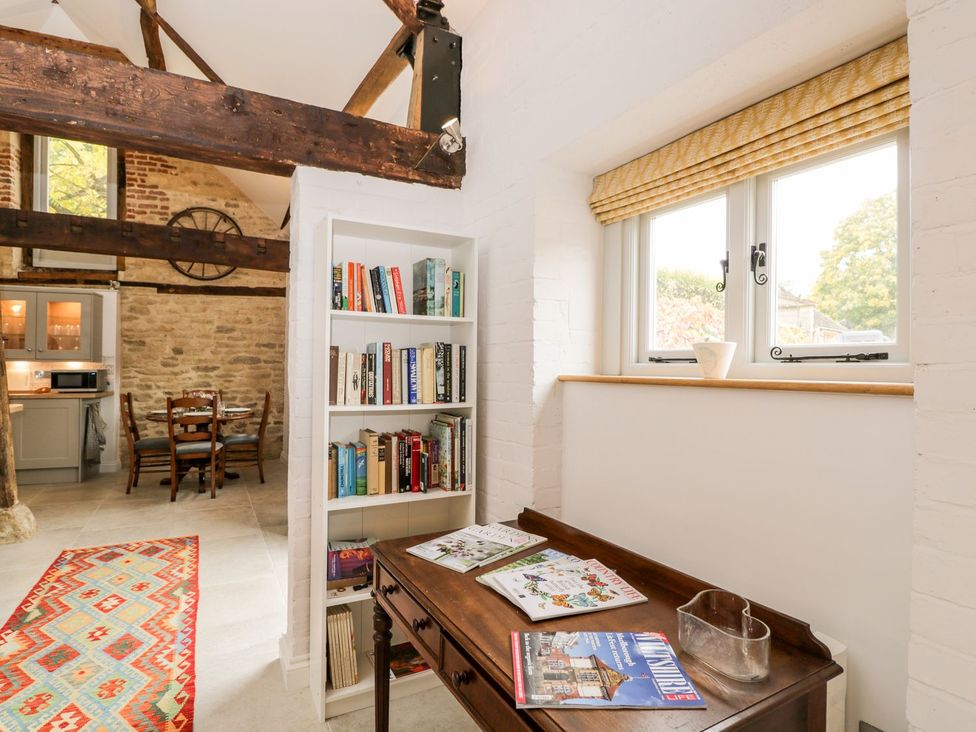 A living room with a bookshelf and a wooden table at The Old Swill House in Foxham
