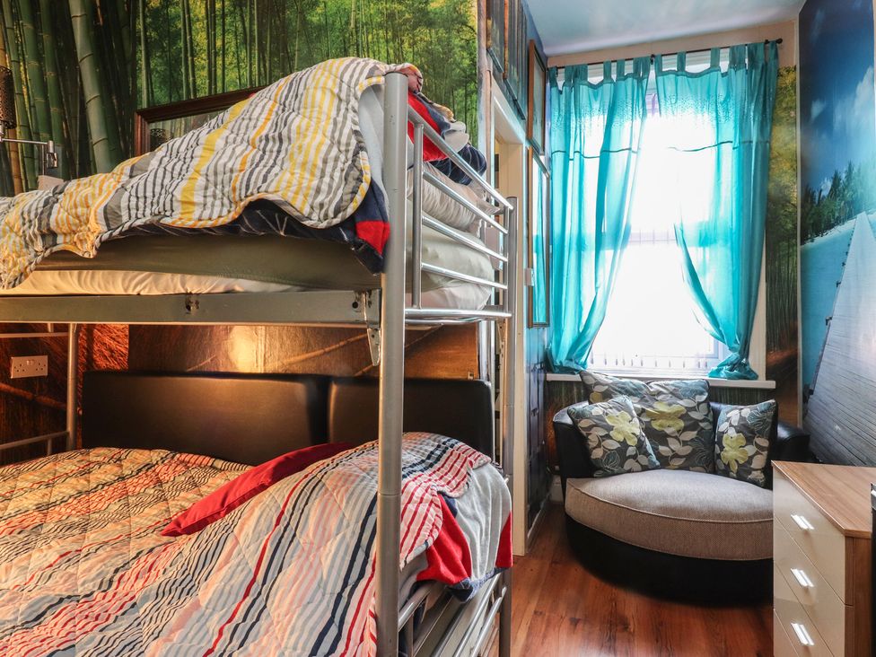 A bedroom with a bunk bed and a cushioned chair at Number 6 in Blackpool