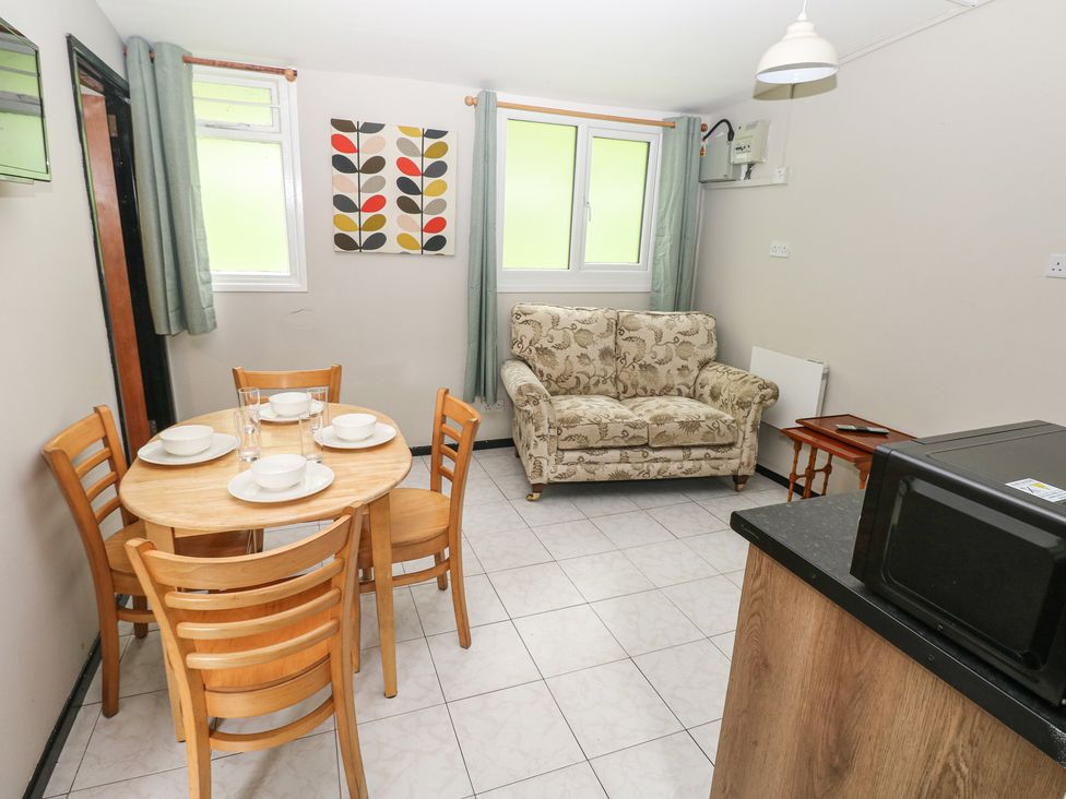 A living room with a table, chairs, and a sofa at Cabin No. 15 - Salt and Fern Cabins Goytre near Port Talbot