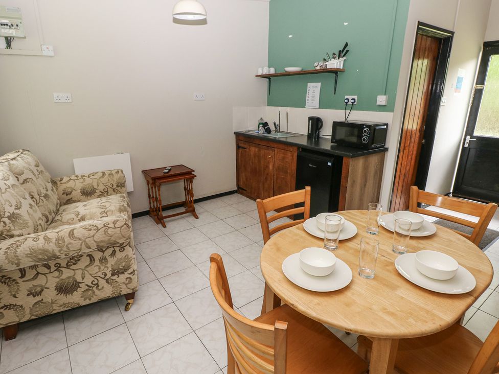 A kitchen and dining area with a table and seating at Cabin No. 15 - Salt and Fern Cabins Goytre near Port Talbot
