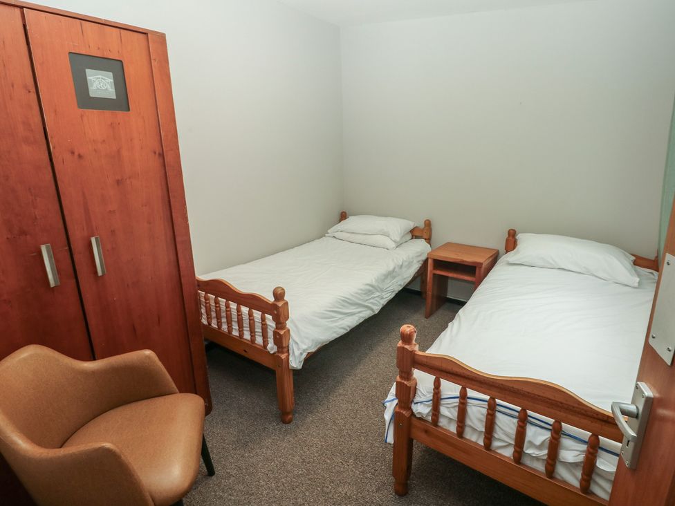 A bedroom with two beds and a wardrobe at Cabin No. 15 - Salt and Fern Cabins Goytre near Port Talbot