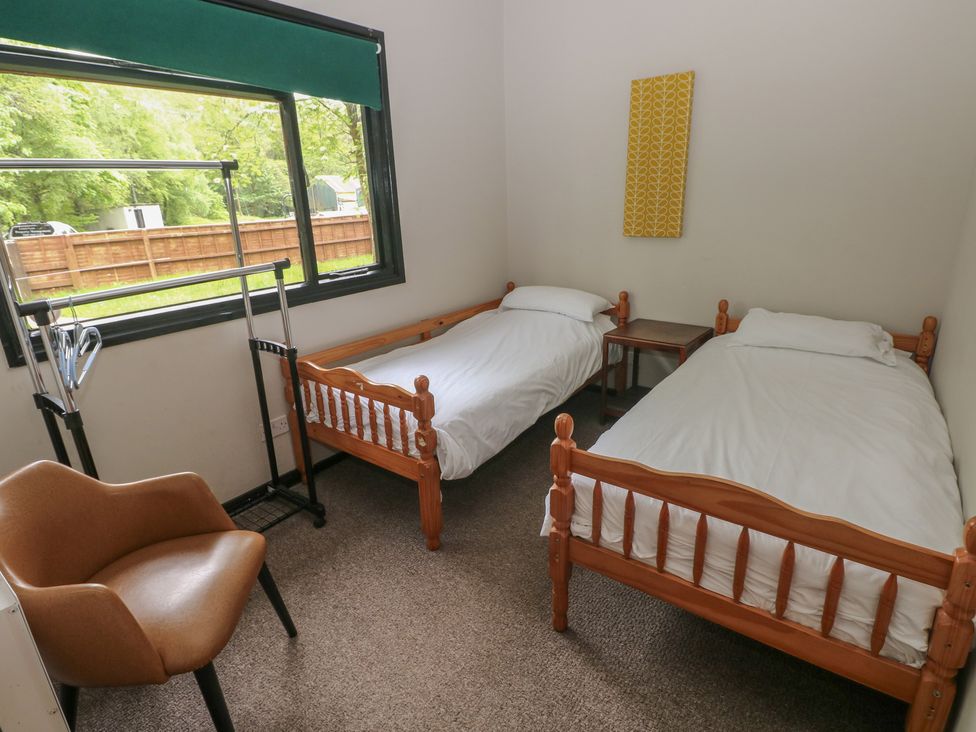 A bedroom with two beds and a chair at Cabin No. 15 - Salt and Fern Cabins in Goytre near Port Talbot