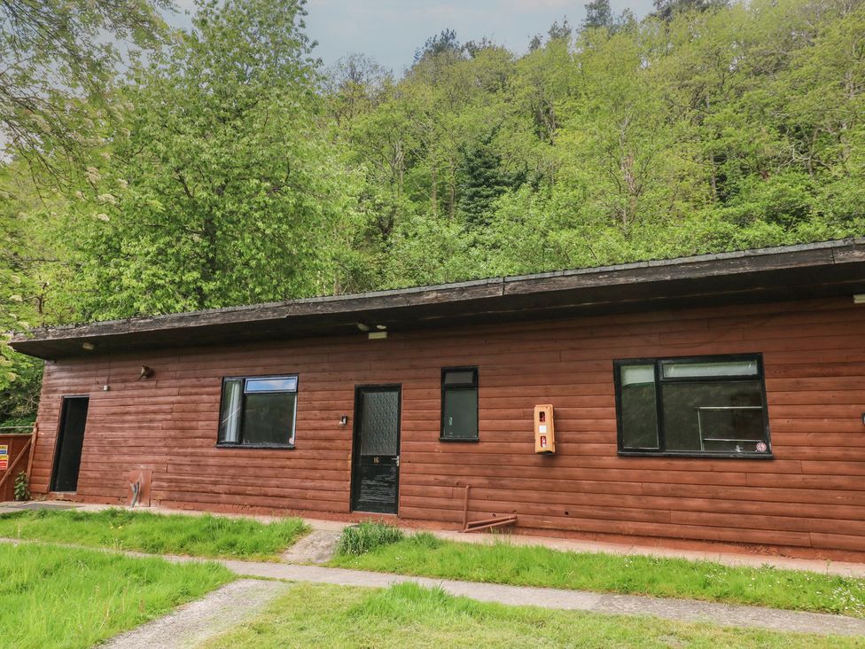 A wooden cabin with windows and a pathway at Cabin No. 16 - Salt and Fern Cabins in Goytre near Port Talbot