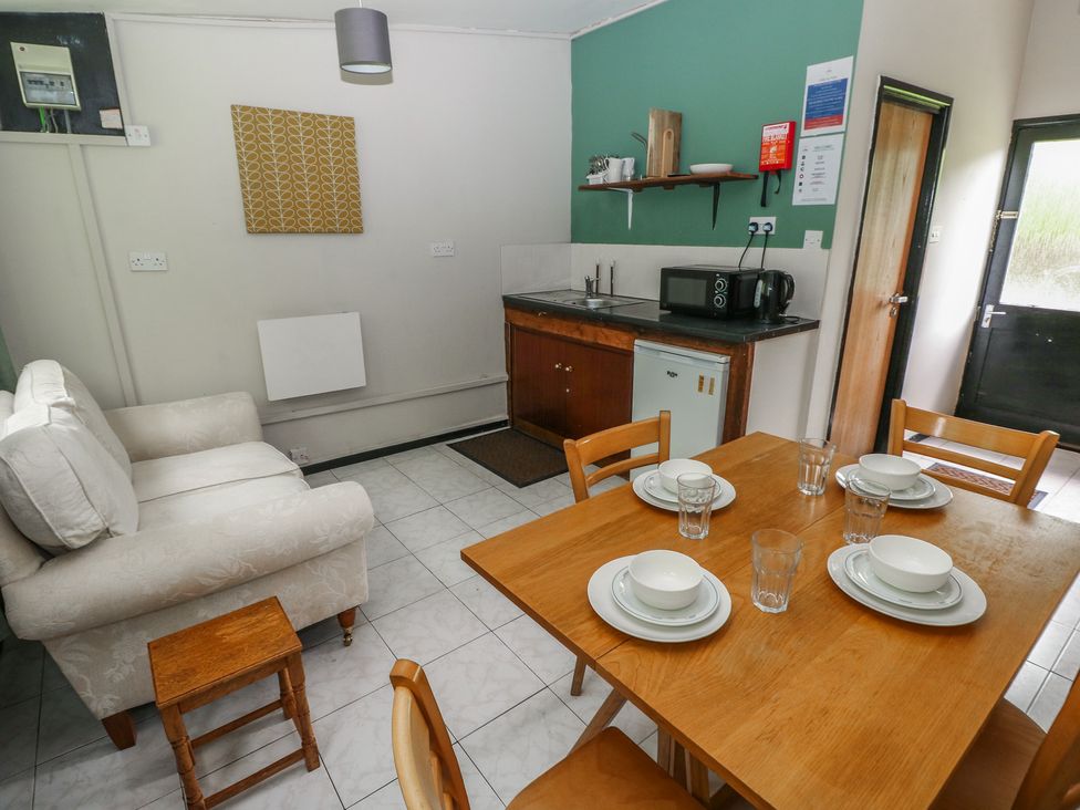 A kitchen with a table set for dining and a microwave at Cabin No. 16 - Salt and Fern Cabins Goytre near Port Talbot