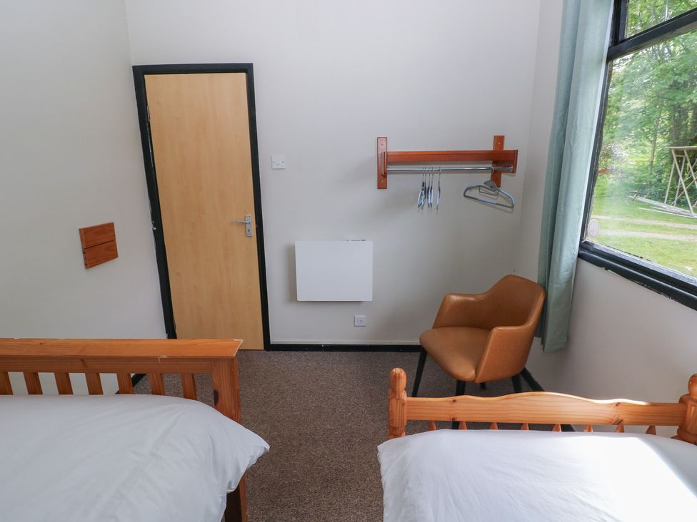 A bedroom with two beds and a chair at Cabin No. 16 - Salt and Fern Cabins Goytre near Port Talbot