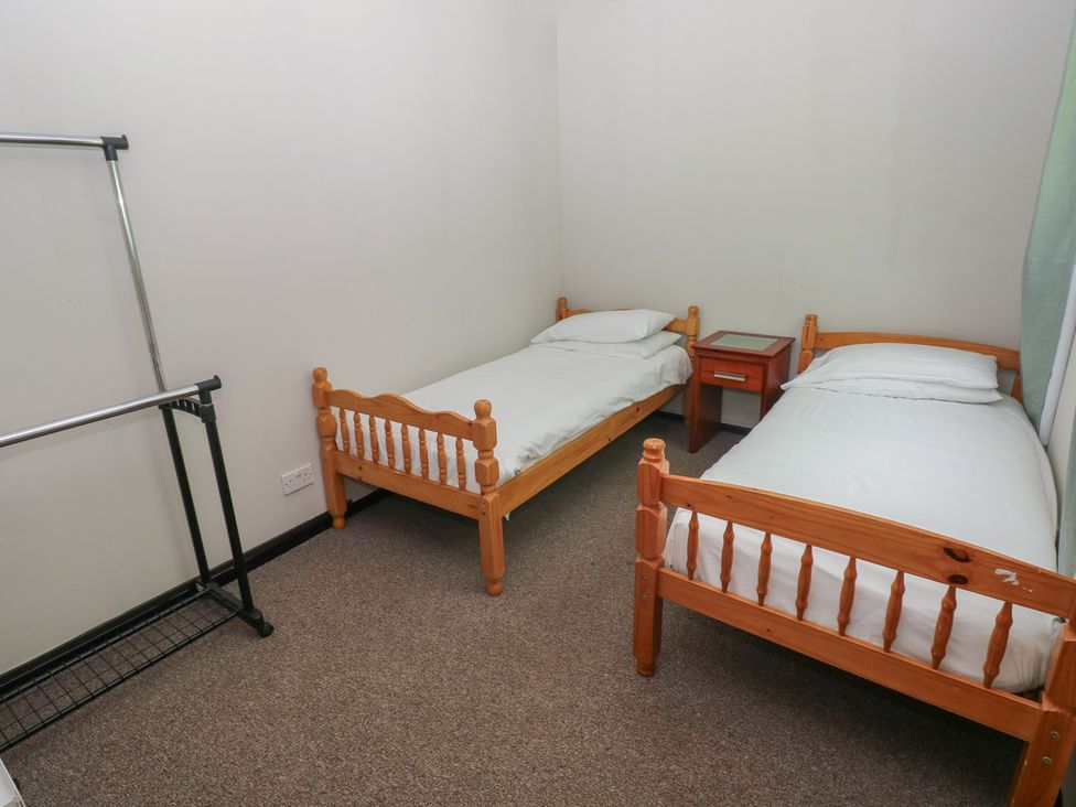 A bedroom with two beds and a clothes rack at Cabin No. 16 - Salt and Fern Cabins Goytre near Port Talbot