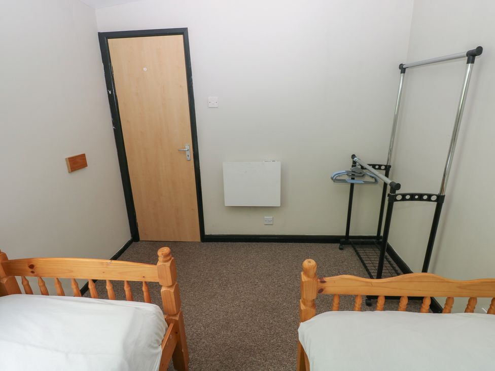 A bedroom with two beds and a clothes rack at Cabin No. 16 - Salt and Fern Cabins Goytre near Port Talbot