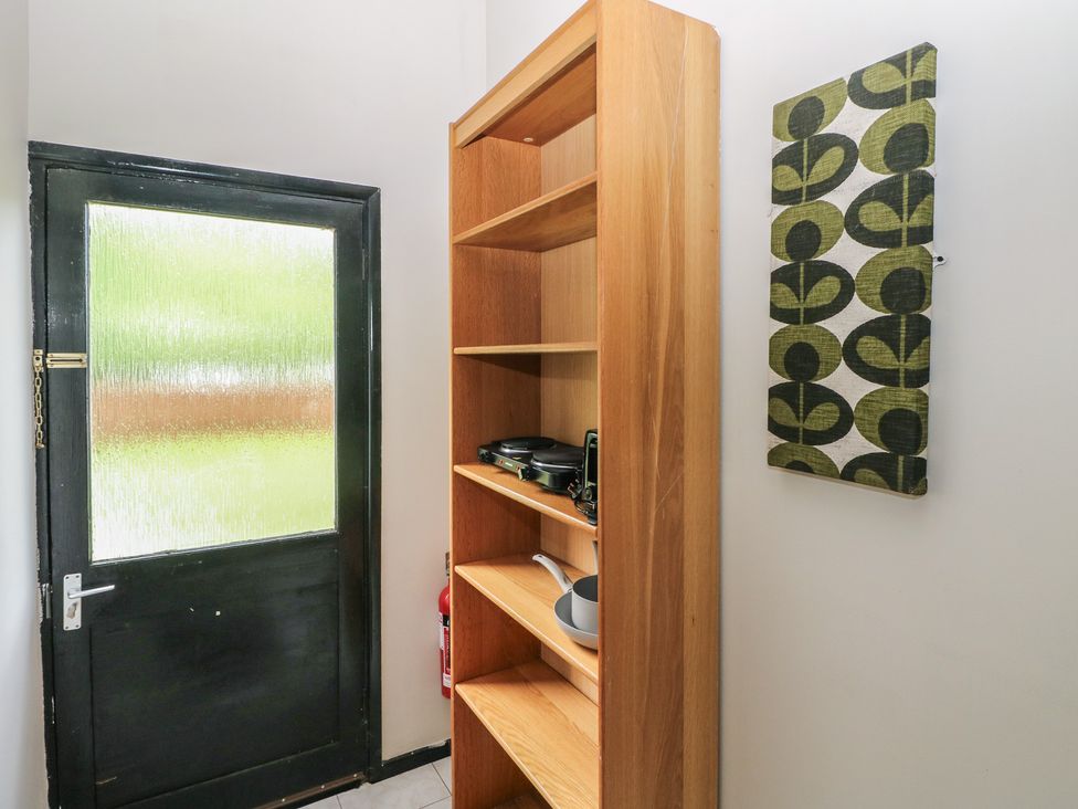 A hallway with a door and shelves containing kitchenware at Cabin No. 16 - Salt and Fern Cabins Goytre near Port Talbot